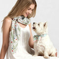 Woman wearing a white botanical floral print scarf with matching dog bandana on a small white terrier